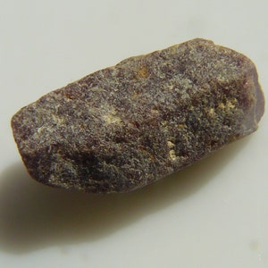 Könnte beinhalten: Ein rauer, dunkelvioletter und grauer Edelstein mit einer leicht länglichen Form.