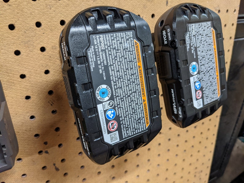 May include: A black Ryobi 18V lithium-ion battery with a warning label and a recycling symbol. The battery is labeled "PBP002" and has a capacity of 1.5 Ah. The battery is made in China.