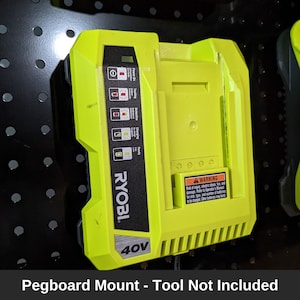 May include: A green and black pegboard mount for a 40V Ryobi battery. The mount has a warning label that reads "A WARNING Risk of injury, electric shock, fire, and damage. Refer to Operator's Manual for safety instructions. Battery must be charged. Other batteries may be incompatible."