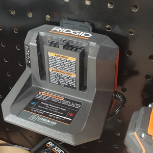 May include: A black and orange Ridgid battery charger with a power cord. The charger has a warning label that reads "Avertissement: Charging Temperature Range 50&deg;F to 104&deg;F (10&deg;C to 40&deg;C)".