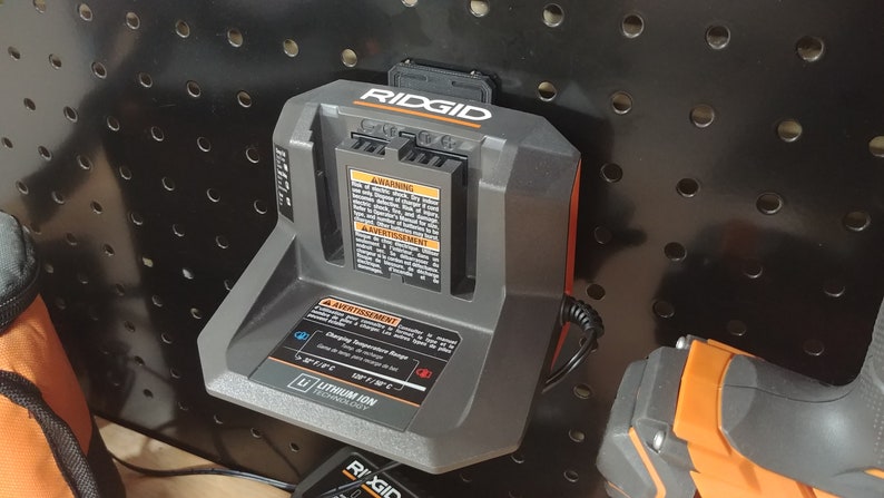 May include: A black and orange Ridgid battery charger with a power cord. The charger has a warning label that reads "Avertissement: Charging Temperature Range 50&deg;F to 104&deg;F (10&deg;C to 40&deg;C)".