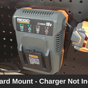 May include: A black and orange RIDGID 18V charger mounted on a pegboard. The charger has a green light indicating it is plugged in. The text "RIDGID 18V" is visible on the charger.