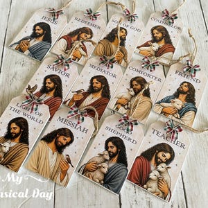 May include: A collection of twelve rectangular wooden tags, each featuring a printed illustration of a bearded figure in robes holding a lamb or bird. Each tag includes a specific title such as Jesus, Redeemer, Savior, or Teacher, and a small plaid bow.