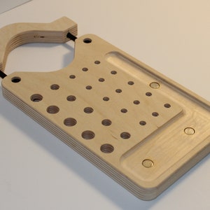 May include: A wooden organizer with a handle, a grid of holes, and a small tray. The organizer is made of light wood and has a natural finish.