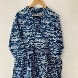 Peut inclure: Robe bleu marine ornée d'un motif de poissons blancs. La robe a des manches longues, un col en V avec un pompon et une taille froncée. Le texte "indianecottondress" est visible sur la robe.