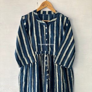 May include: A long-sleeved, blue and white striped dress with a button-up collar and a tie at the waist. The dress is made of cotton and has a relaxed fit.