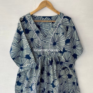 Puede incluir: Un vestido de algodón azul y blanco con estampado floral. El vestido tiene un escote en V y mangas 3/4. El vestido está fruncido en la cintura y tiene una falda de capas.