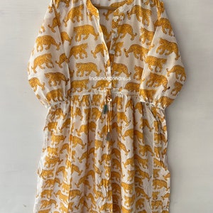 May include: White cotton dress with a yellow tiger print. The dress has a V-neckline, 3/4 sleeves, and a drawstring waist. The dress is made in India and is available in sizes S-XL.