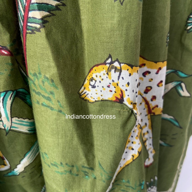 May include: Green fabric with a white and yellow leopard print design. The fabric has a textured, linen-like appearance. The text "indiancottondress" is visible in the lower left corner of the image.