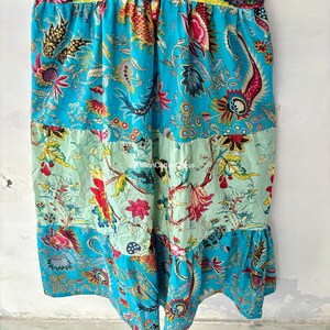 May include: A blue and green cotton skirt with a floral print. The skirt has a tiered design and a ruffled hem.
