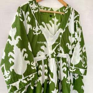 May include: A green and white printed cotton dress with a V-neckline and 3/4 sleeves. The dress has a gathered waist and a relaxed fit. The fabric is soft and comfortable. "IndianCottonDress" is printed on the dress.