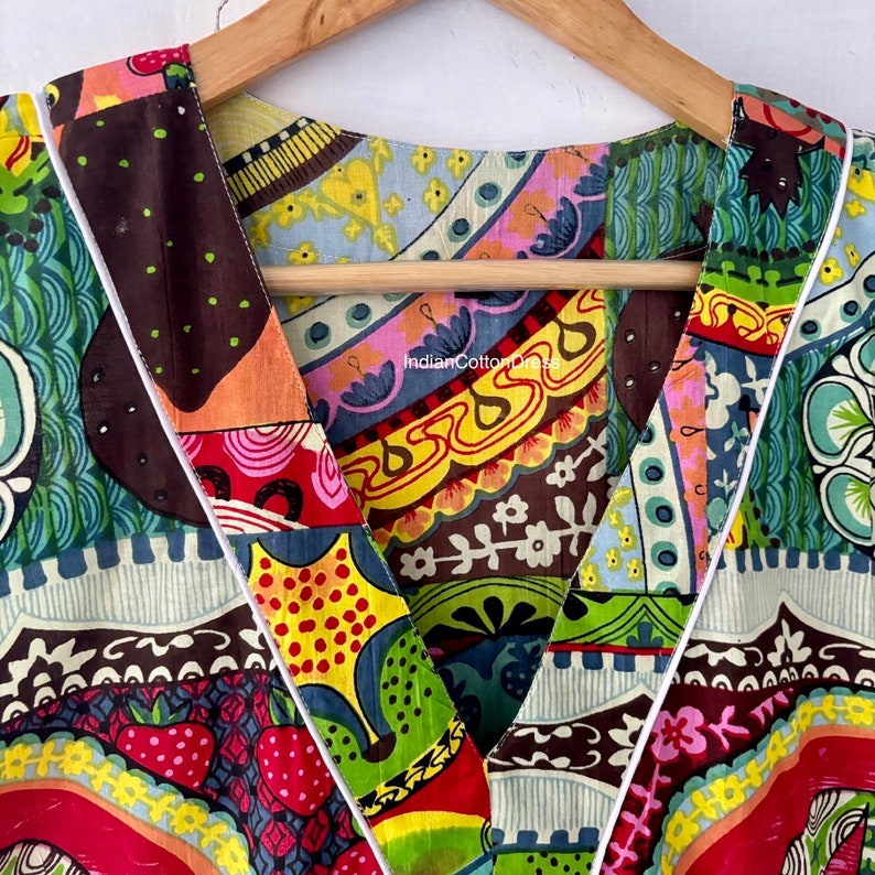 May include: Close-up of a colorful, patterned fabric with a V-neckline. The fabric is made of a patchwork of different prints, including floral, geometric, and abstract designs. The fabric is trimmed with a white piping.