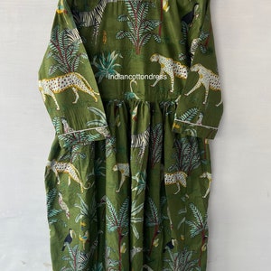 May include: A green cotton dress with a white trim. The dress features a print of leopards, zebras, and tropical plants. The text "indiancottondress" is printed on the dress.
