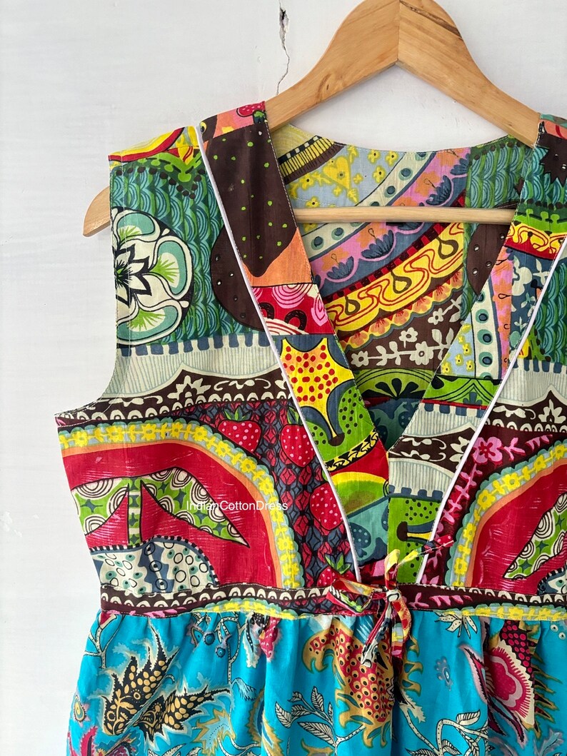 May include: A colorful, patterned sleeveless dress with a V-neckline and a tie at the waist. The dress is made of cotton and has a patchwork design.
