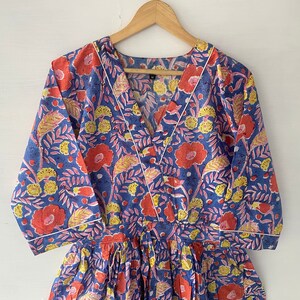 May include: A blue and white floral print dress with a V-neckline and 3/4 sleeves. The dress has a white trim around the neckline and sleeves.