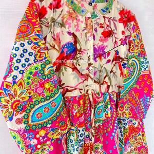 May include: A long-sleeved, button-up dress with a colorful paisley print. The dress has a gathered skirt and a tie at the waist. The fabric is a blend of cotton and silk.