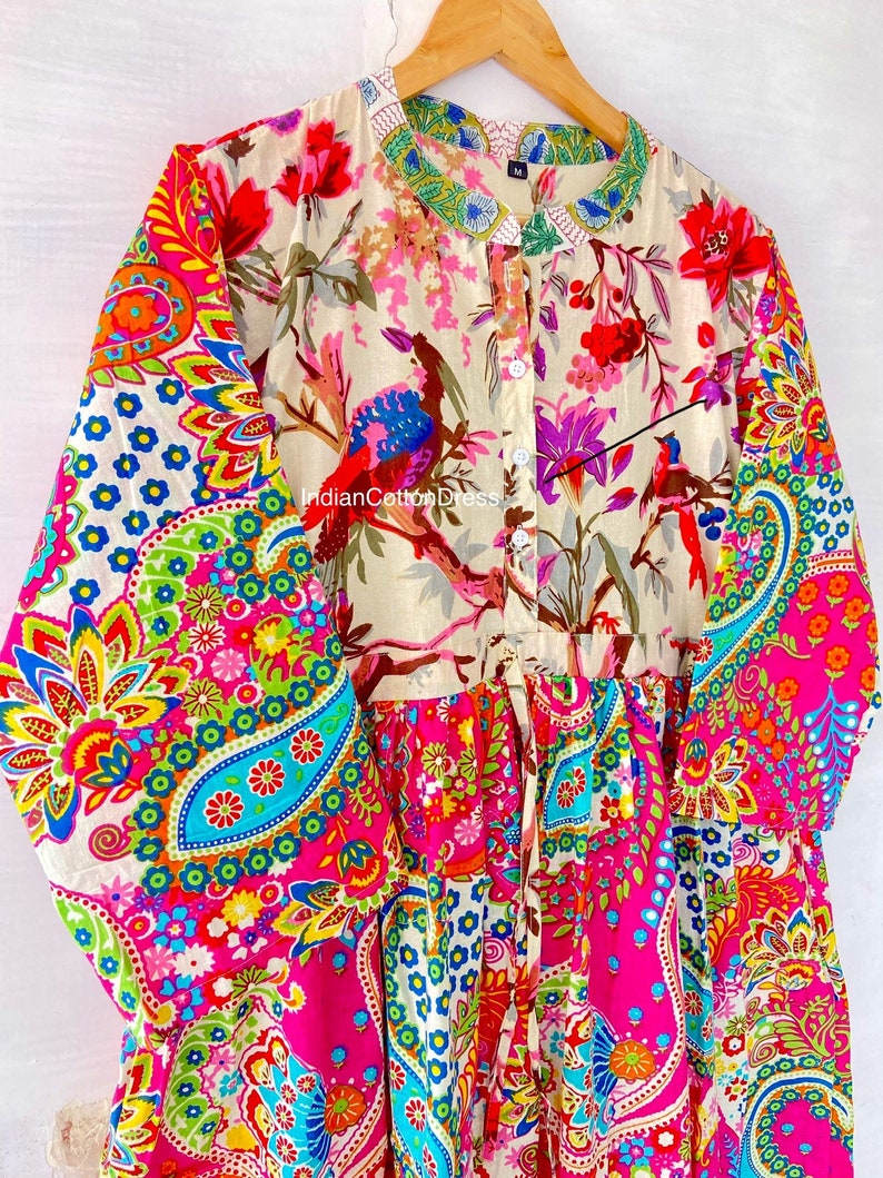 May include: A long-sleeved, button-up dress with a colorful paisley print. The dress has a gathered skirt and a tie at the waist. The fabric is a blend of cotton and silk.