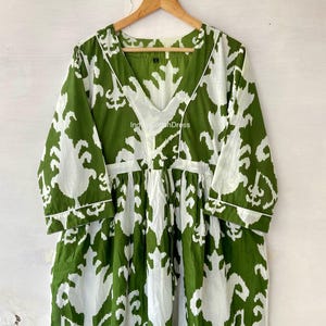 May include: A green and white cotton dress with a V-neck and 3/4 sleeves. The dress has a floral pattern and a drawstring waist. The text "IndianCottonDress" is visible on the dress.