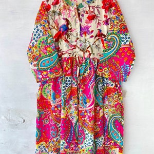 May include: A long-sleeved, colorful dress with a paisley print. The dress has a button-up front and a gathered waist. The dress is made of cotton and is available in a variety of sizes.