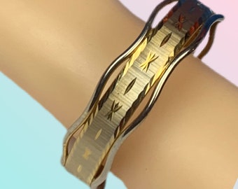 Peut inclure: Un bracelet jonc en or et argent avec un design ondulé et une surface texturée.
