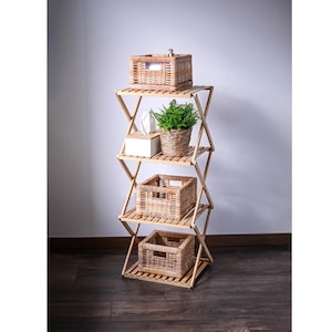 Op de afbeelding: Een houten rek met vier planken, elk met een geweven mand of een plant. De planken zijn gemaakt van natuurlijk hout en hebben een rustieke uitstraling. De manden zijn gemaakt van natuurlijke materialen en hebben een lichtbruine kleur. De plant is een kleine varen met groene bladeren. Het rek staat op een houten vloer.