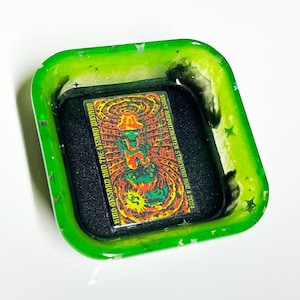 May include: A green square-shaped tray with a black and white image of a concert poster. The poster features a green alien-like figure with a hat and the text "Who Destroyed the World?" and "1997 Summerfest, Stroud, MO, July 4, 2024."