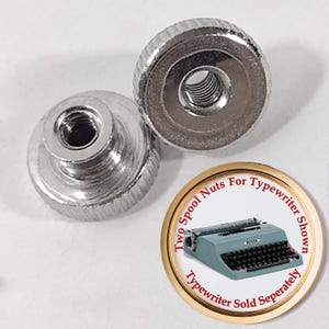 May include: Two silver metal spool nuts for a typewriter. The nuts have a threaded hole in the center and a knurled edge. The image also shows a vintage blue typewriter with the text "Two Spool Nuts For Typewriter Shown Typewriter Sold Separately".