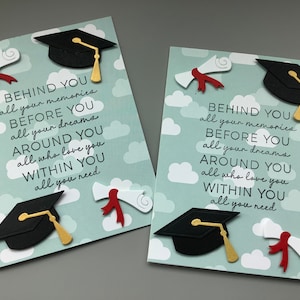 May include: Two graduation cards with a blue background and white clouds. The cards feature a black graduation cap, a red and white diploma, and the text "BEHIND YOU all your memories BEFORE YOU all your dreams AROUND YOU all who love you WITHIN YOU all you need".