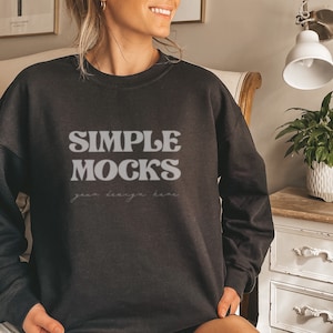 Peut inclure: Un sweat-shirt noir avec le texte "SIMPLE MOCKS" dans une police r&eacute;tro. Le texte "your design here" est &eacute;crit en plus petit en dessous du texte principal.