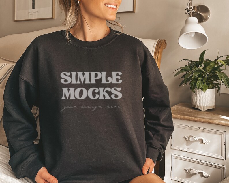 Peut inclure: Un sweat-shirt noir avec le texte "SIMPLE MOCKS" dans une police r&eacute;tro. Le texte "your design here" est &eacute;crit en plus petit en dessous du texte principal.