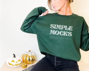 May include: A woman wearing a dark green sweatshirt with the text "SIMPLE MOCKS" in white. The sweatshirt is a mock-up for a design.