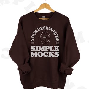 Puede incluir: Una sudadera marrón con el texto "YOUR DESIGN HERE" en un círculo con un diseño de estrella en su interior. El texto "ESTD 2021" está debajo del círculo. El texto "SIMPLE MOCKS" está debajo del círculo en una fuente más grande.