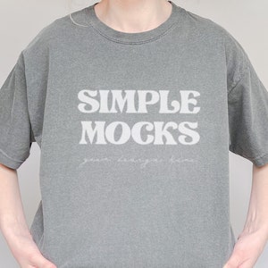 Può includere: Una maglietta grigia con il testo "SIMPLE MOCKS" in lettere bianche. Il testo è in uno stile di font retrò.