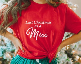 Op de afbeelding: Rood T-shirt met witte tekst die "Last Christmas as a Miss" luidt.
