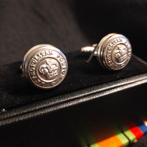 May include: A pair of silver cufflinks with a crown and the words "Metropolitan Police" engraved on the front.