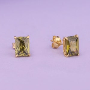 May include: A pair of gold earrings with square green gemstones.