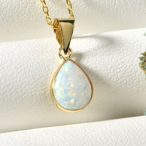 May include: A gold chain necklace with a teardrop-shaped white opal pendant.