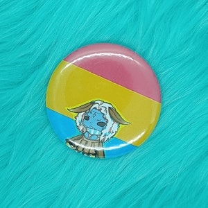 Könnte beinhalten: Ein runder Knopf mit einer Comicfigur auf einem Hintergrund aus gelben, blauen und rosa Streifen. Die Figur ist ein blaues und weißes Wesen mit einer gelben Krone und einem braunen Rock.