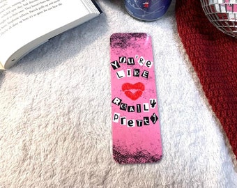 May include: Pink bookmark with black and white text that reads "You're Like Really Pretty" with a red lip print.