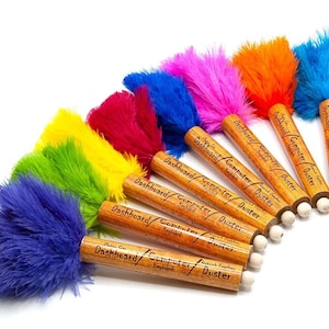 Peut inclure: Un ensemble de huit plumeaux en plumes colorées avec des manches en bois. Chaque plumeau porte l'inscription "Dashboard/Computer/Duster" imprimée sur la poignée.