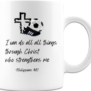 May include: White ceramic mug featuring a soccer ball, a soccer cleat, and a cross graphic. The mug has the text "I can do all things through Christ who strengthens me" and "Philippians 4:13" in black script.