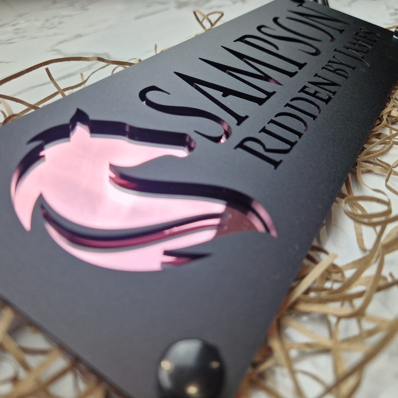 May include: Black wooden sign with a pink horse silhouette and the text "SAMPSON RIDDEN BY JAMES"