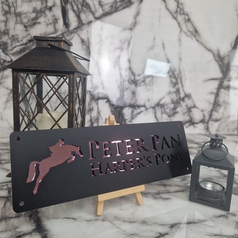 May include: Black metal sign with a rose gold horse silhouette and the text "PETER PAN HARPER'S PONY".