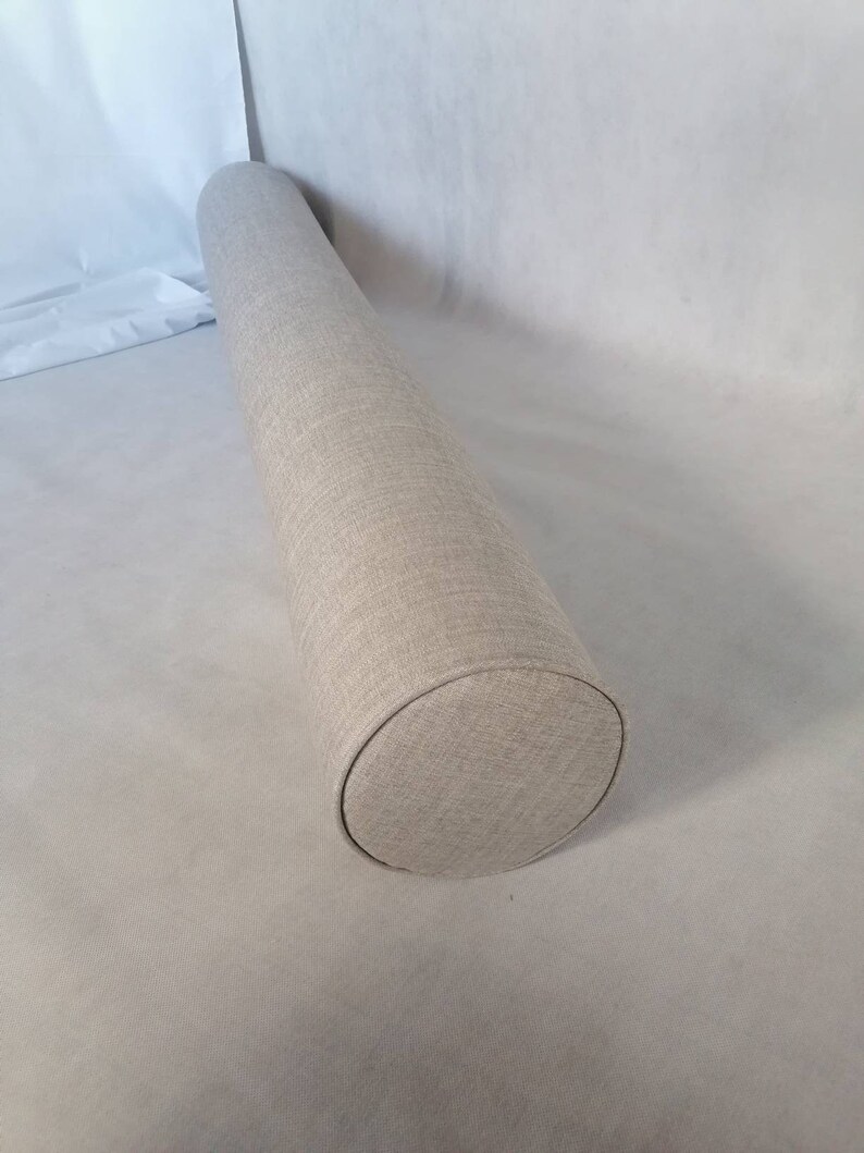 May include: A beige cylindrical pillow with a textured fabric cover.