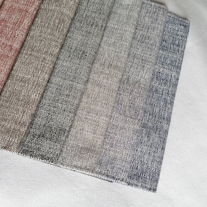 May include: A close-up of eight fabric swatches in various shades of gray, beige, and pink. The swatches are arranged in a row, with the pink swatch at the top and the darkest gray swatch at the bottom.