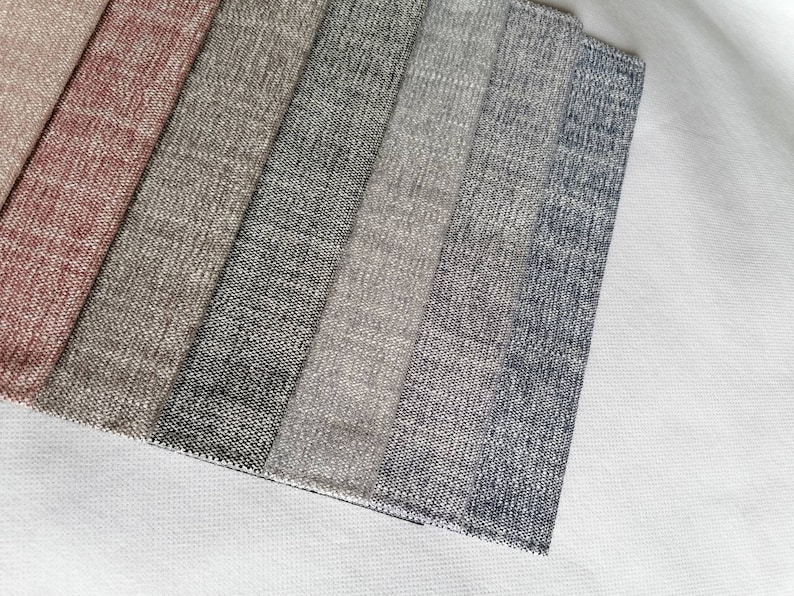 May include: A close-up of eight fabric swatches in various shades of gray, beige, and pink. The swatches are arranged in a row, with the pink swatch at the top and the darkest gray swatch at the bottom.