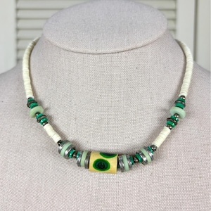 May include: A white ceramic mug with a black handle and the text "But First, Coffee" in a black, bold font. The mug is on a white surface.