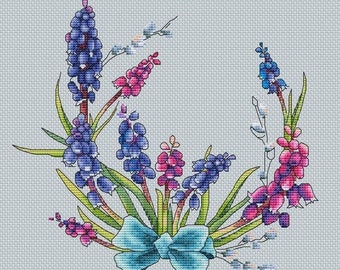Könnte beinhalten: Ein Kreuzstichmuster mit einem Strauß aus blauen und rosa Blumen mit einer blauen Schleife. Die Blumen sind in einem Kreis angeordnet, wobei die Schleife in der Mitte liegt.