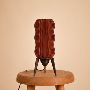 Wavy x Amber L table lamp product photo. Unique textured amber body made from recycled plastic sits on a retro tripod base. This eco-friendly lamp offers mid-century modern & space age style for warm ambient lighting (shown unlit).