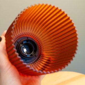 Overhead shot of DIABOLO lamp highlighting gentle curves and amber light. Handcrafted from recycled plastic, providing an eco-friendly lighting solution. Perfect for adding warm ambient light to bedside tables, living rooms, or reading nooks.